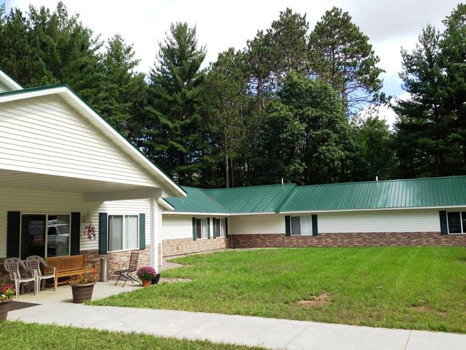 A single-story residential building surrounded by a grassy lawn and trees.