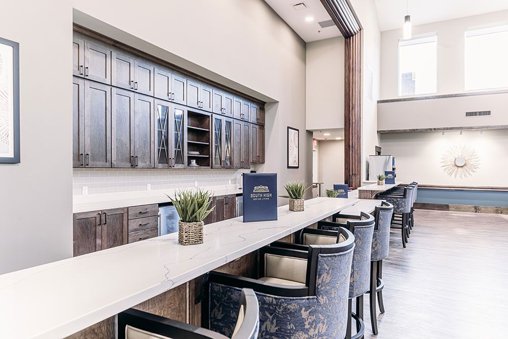 A modern reception area with a long counter, stylish chairs, and decorative plants.