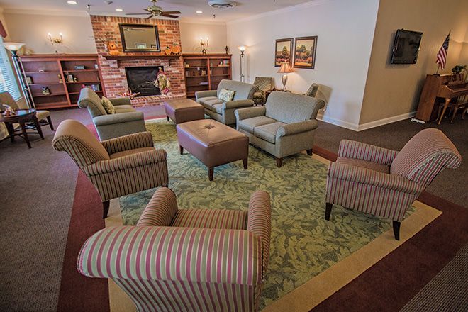 A cozy living room with comfortable seating, featuring armchairs and a sofa arranged around a fireplace.