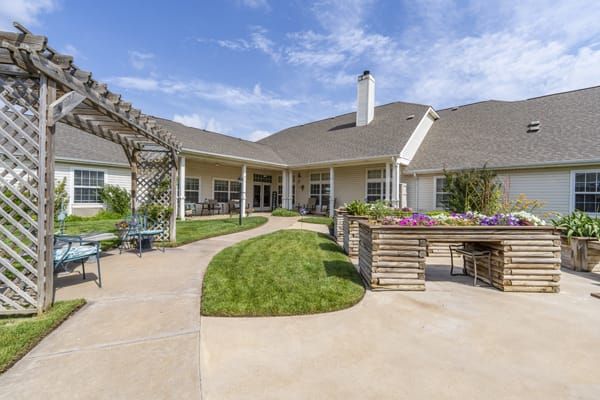 A spacious backyard with a well-maintained garden and outdoor seating area under a clear blue sky.