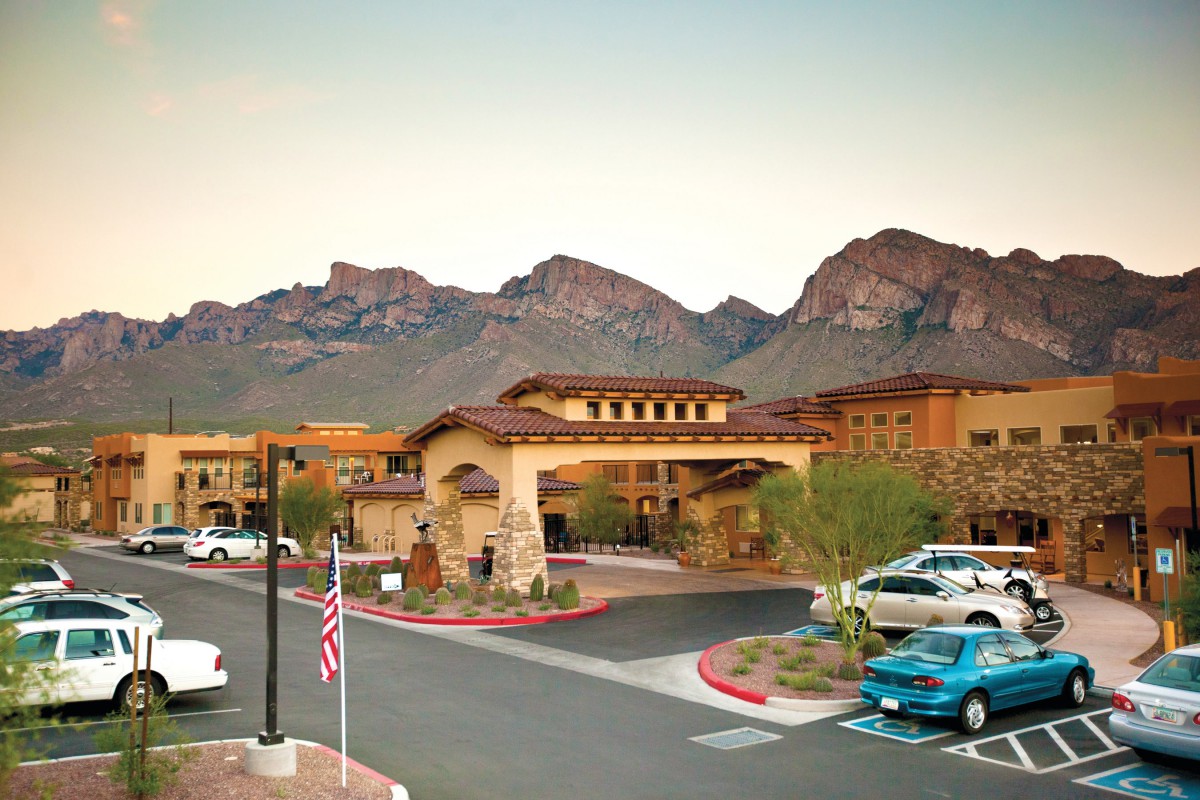A picturesque resort nestled in a desert landscape with mountains in the background at sunset.