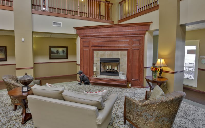 A cozy living room featuring a central fireplace, surrounded by comfortable seating and warm decor.