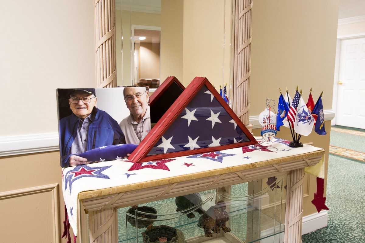 A neatly folded American flag displayed on a table, accompanied by a framed photograph and decorative elements.