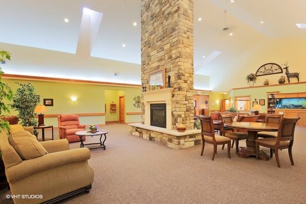 A spacious and cozy living room with a central stone fireplace and comfortable seating.