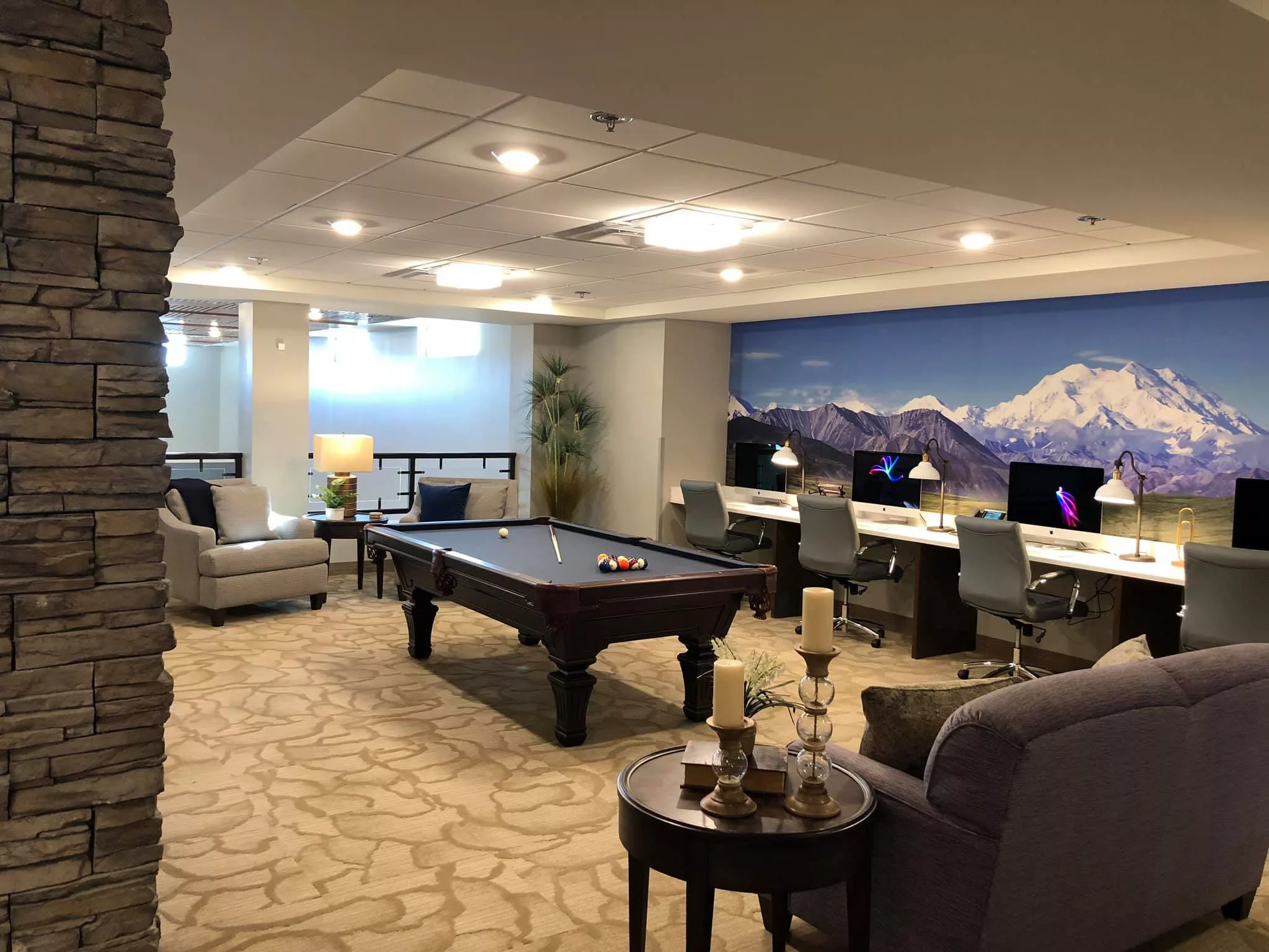 A modern recreation room featuring a pool table, multiple computer workstations, and a comfortable seating area.
