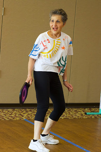 A senior woman engaging in an active exercise session, wearing colorful attire and showcasing joy in movement.