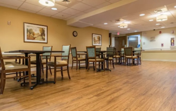 A cozy dining area with wooden flooring and neatly arranged tables and chairs.