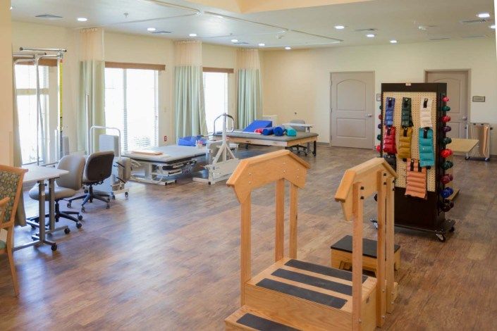 A spacious rehabilitation center featuring therapy tables and exercise equipment.