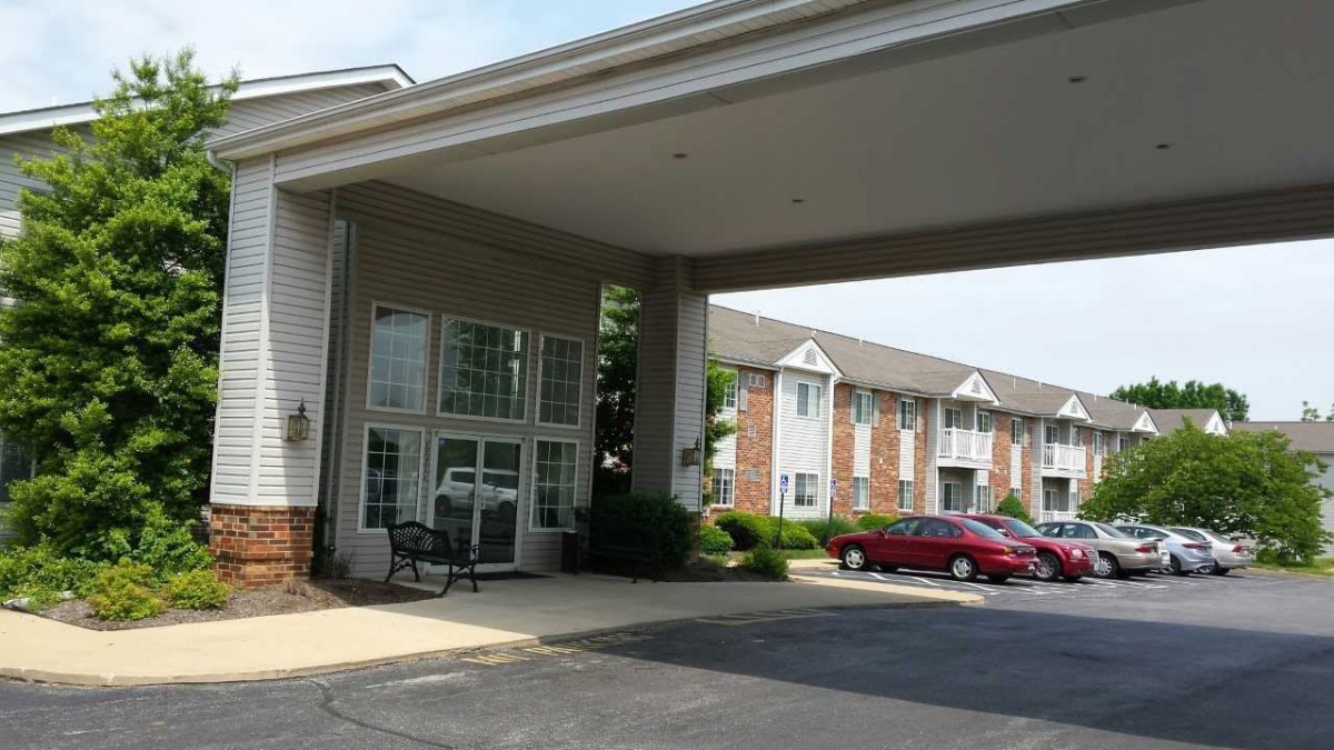 The entrance of a hotel with cars parked in the front.