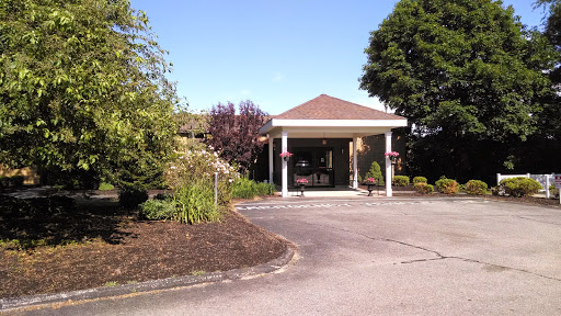 A welcoming entrance to a building surrounded by well-maintained landscaping on a sunny day.