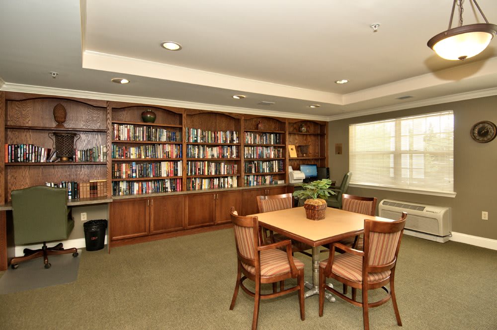 A cozy library room with bookshelves, a table, and chairs suitable for reading and studying.
