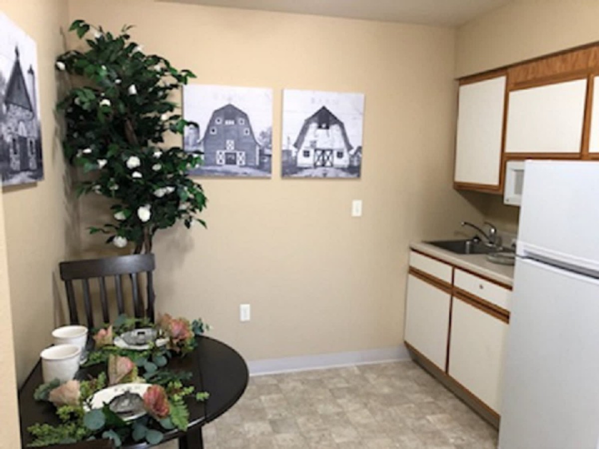 A cozy kitchen and dining area featuring a table set for dining, artwork on the wall, and an indoor plant.