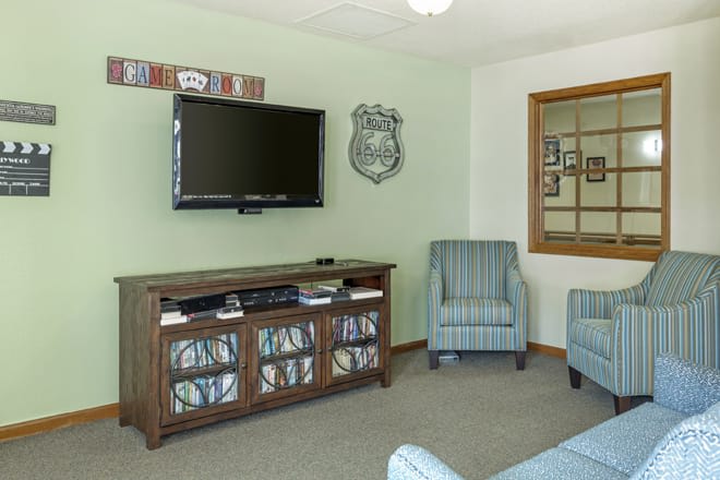 A cozy living room featuring a wall-mounted television, an entertainment center, and comfortable armchairs.