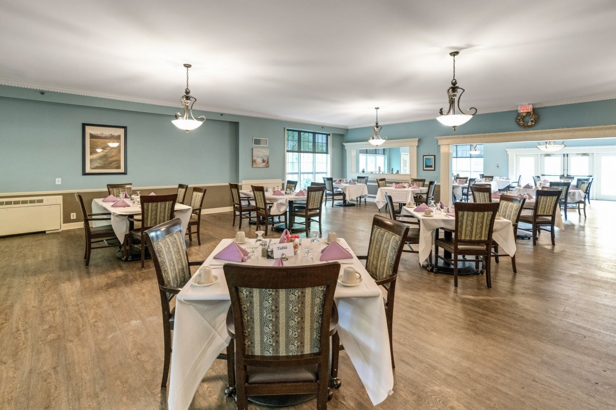 A well-lit dining area featuring elegantly set tables and comfortable chairs.