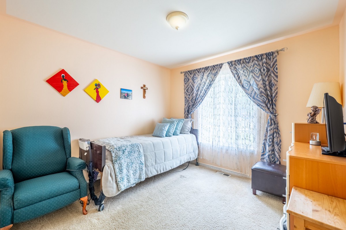 A cozy bedroom with a twin bed, armchair, and decorative wall art.