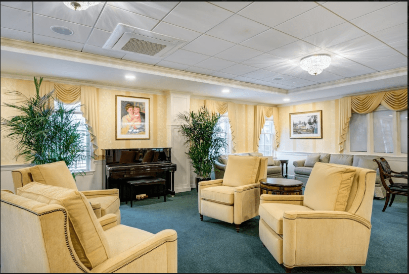A well-appointed living room featuring comfortable chairs, a piano, and decorative artwork.