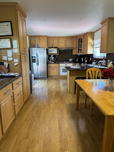 A cozy and modern kitchen featuring wooden cabinets, stainless steel appliances, and a dining area.
