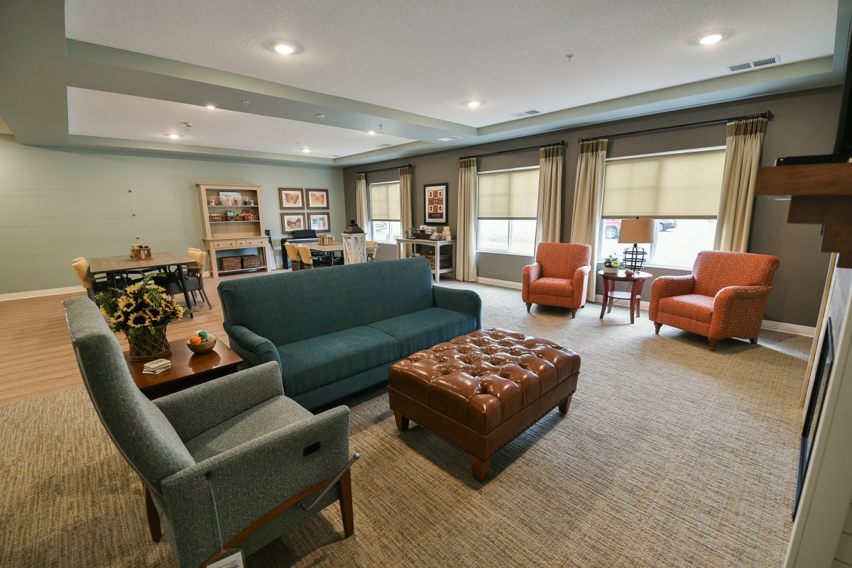 A cozy living room with a sofa, armchairs, and a coffee table, featuring warm decor and ample natural light.