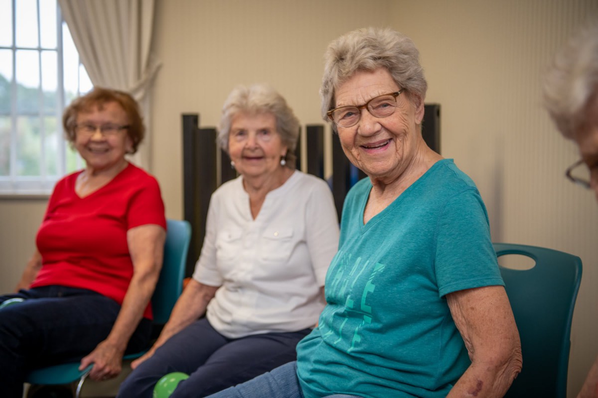 A group of smiling senior women sitting together indoors.