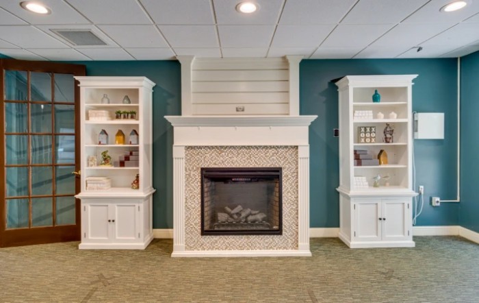 A cozy living room with a central fireplace flanked by built-in shelves, set against a teal accent wall.