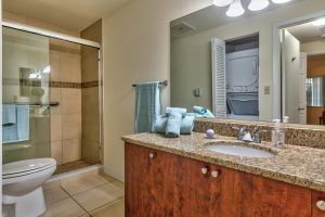 A modern bathroom with a shower, sink, and wooden vanity.