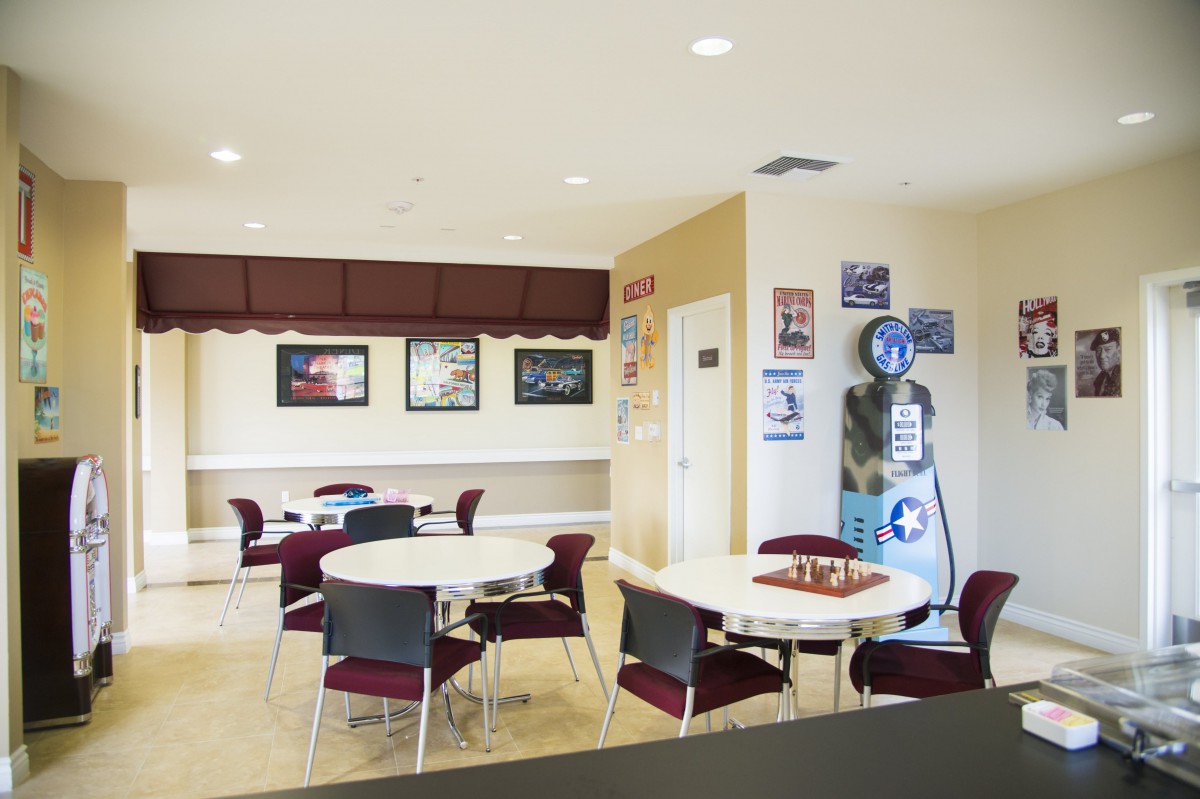 A well-lit waiting room with round tables and chairs, decorated with vintage posters.