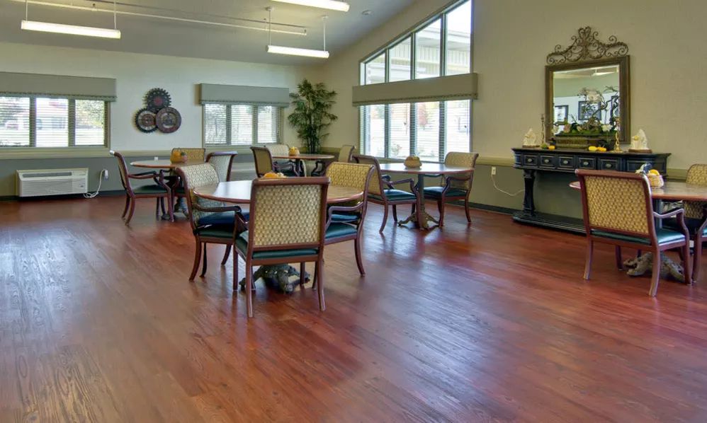 A well-lit dining room with hardwood floors, tables, and chairs arranged neatly.