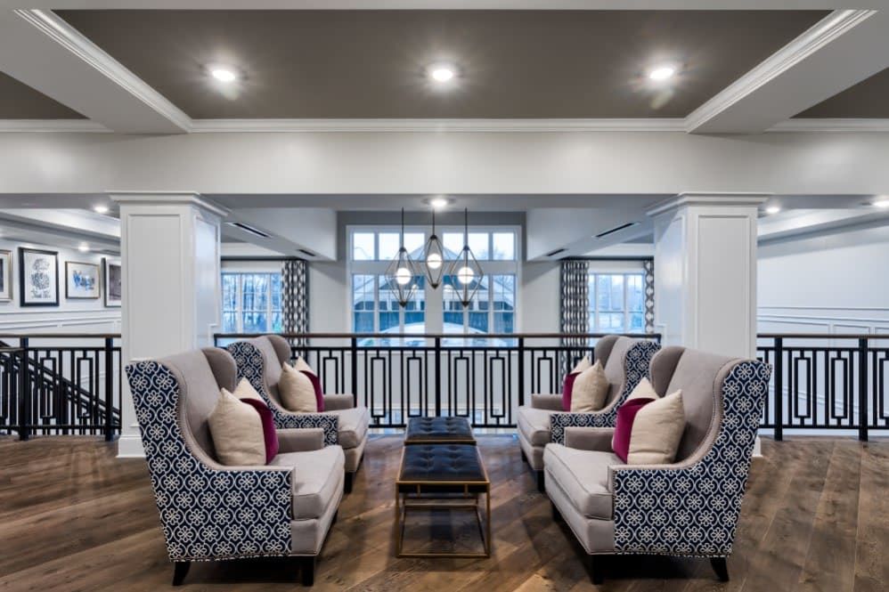 A modern living room with stylish armchairs and a central coffee table, accented by decorative pillows and ceiling lights.