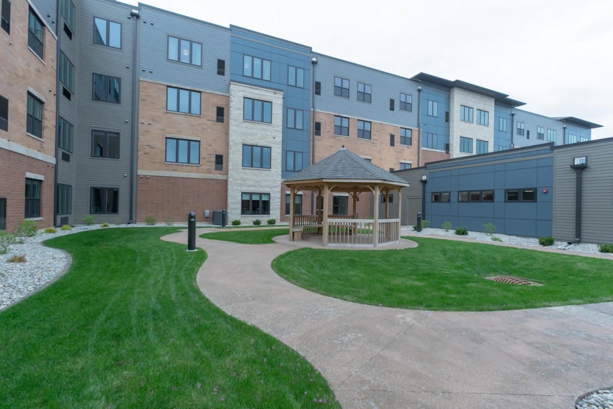 A modern apartment complex with a central gazebo and well-maintained lawn.