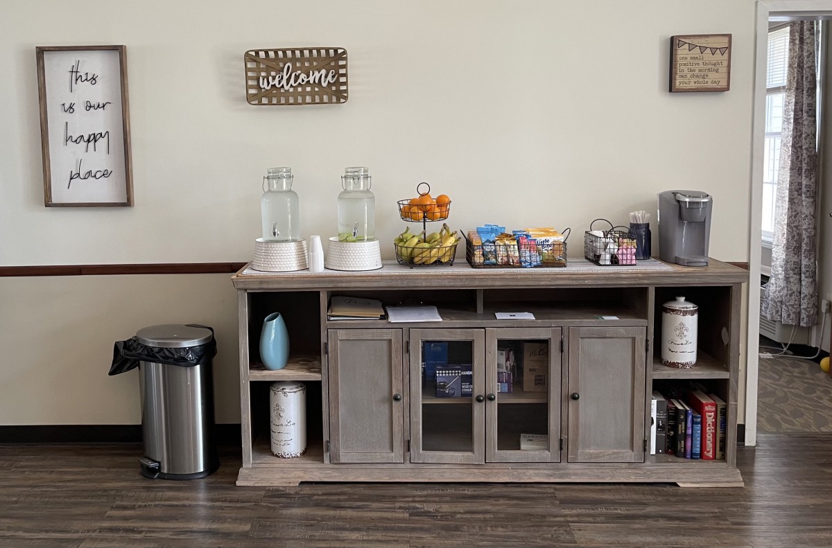 A neatly organized refreshment station with drinks, snacks, and coffee supplies.