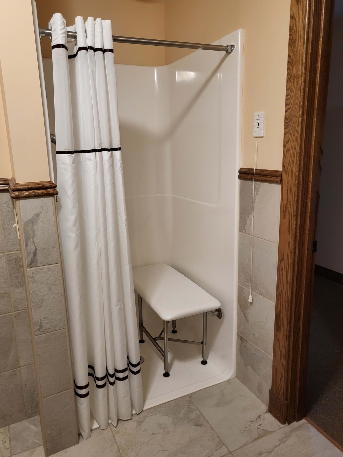 Compact shower area with a curtain and a foldable seat.