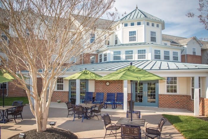 Outdoor patio area with green umbrellas and seating in front of a residential building.