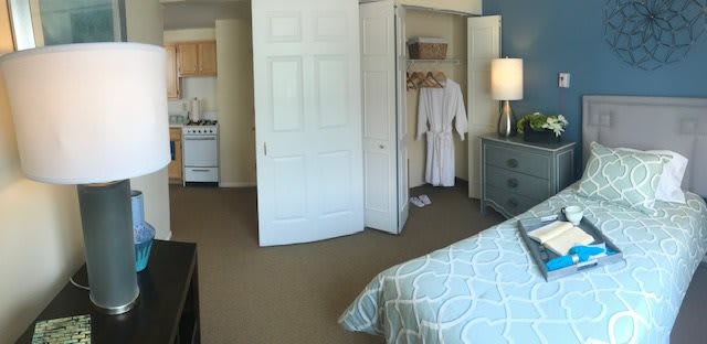 A cozy bedroom with an open closet and a glimpse of a kitchen area.