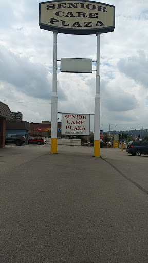 A view of the Senior Care Plaza sign in a commercial area, showcasing available parking.