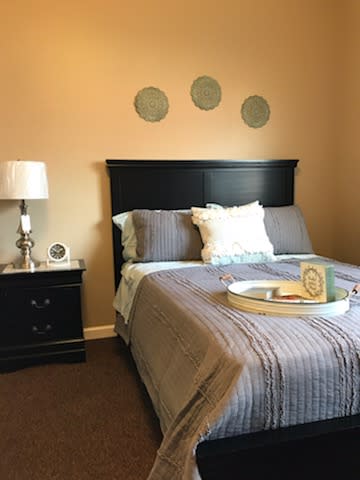 A cozy bedroom with a neatly made bed, bedside table, and decorative elements on the wall.