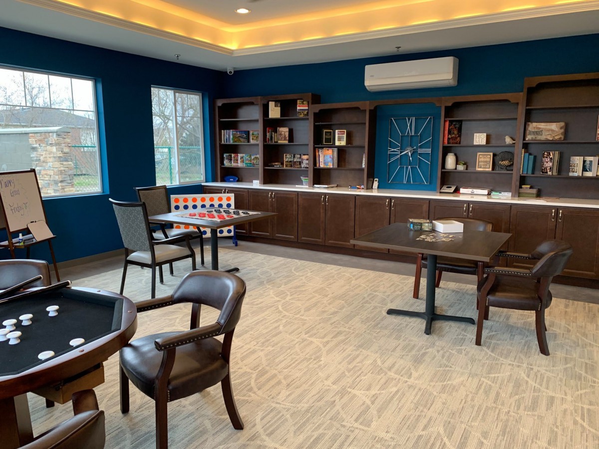 A cozy library room with bookshelves, tables, and chairs for reading.