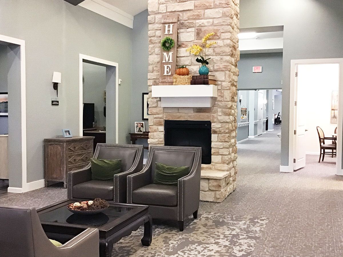 A cozy living room with a stone fireplace and modern decor, featuring comfortable armchairs and subtle lighting.
