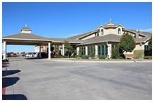 A large building with a covered driveway entrance under a clear blue sky.