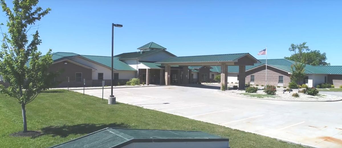 A modern healthcare facility with a green roof and spacious entrance.