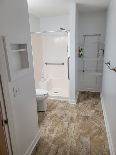 A modern bathroom featuring a shower, toilet, and functional storage.