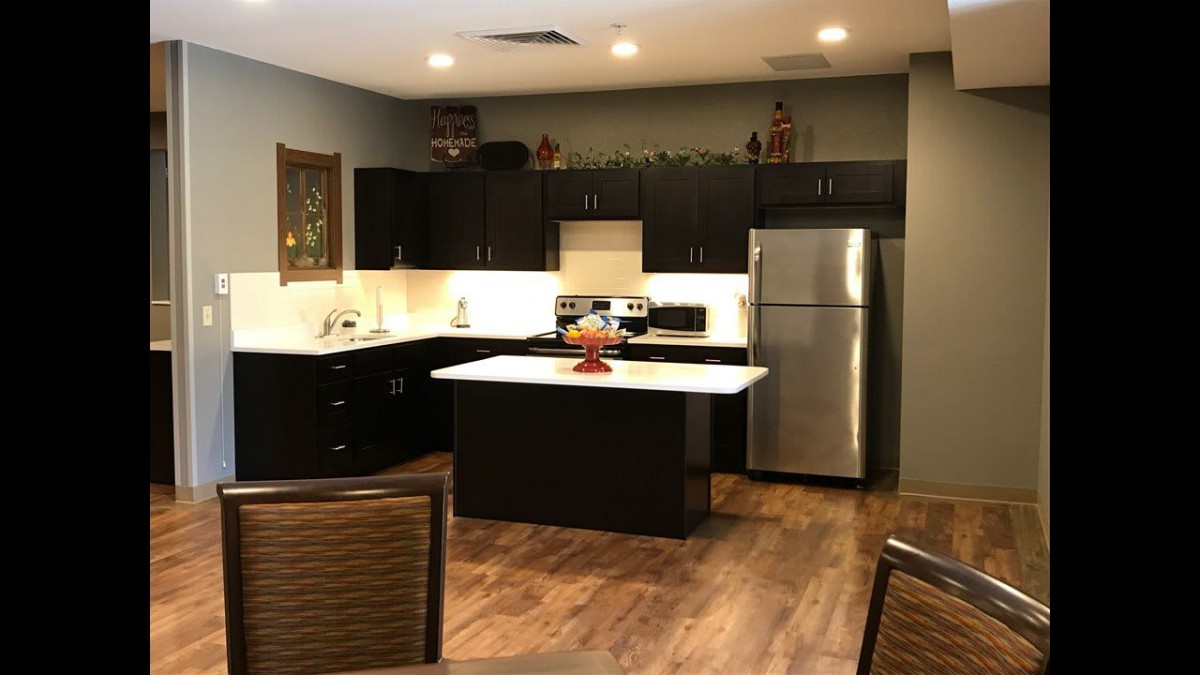 A modern kitchen with dark cabinets, a kitchen island, and stainless steel appliances.