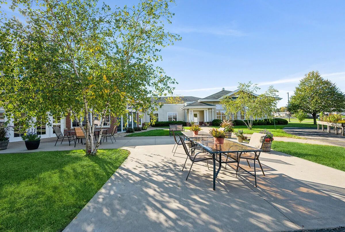 A spacious patio with outdoor furniture and trees in a sunny garden setting.