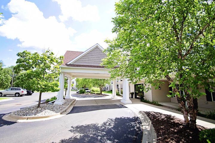 A building entrance with a covered driveway surrounded by trees.