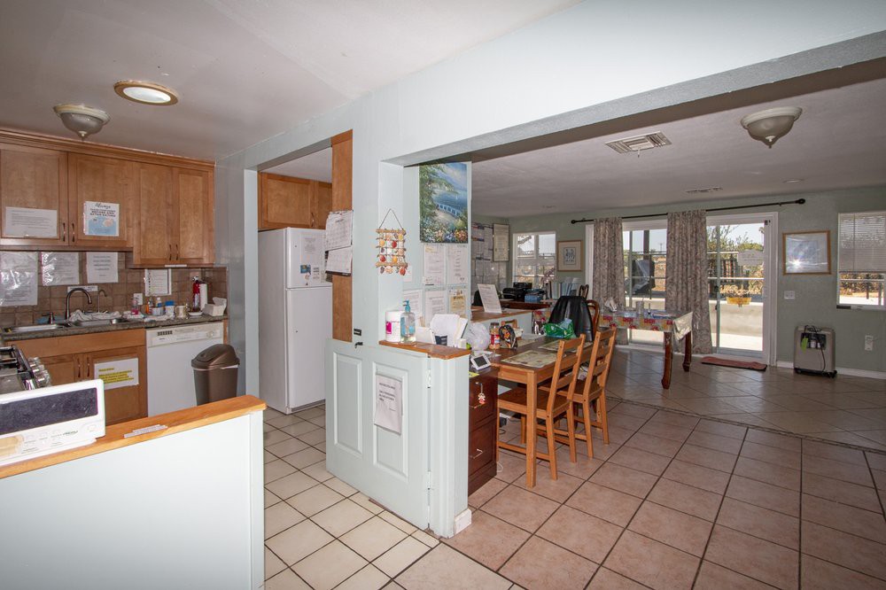 An open floor plan kitchen and dining area with tiled floors and wooden furniture.