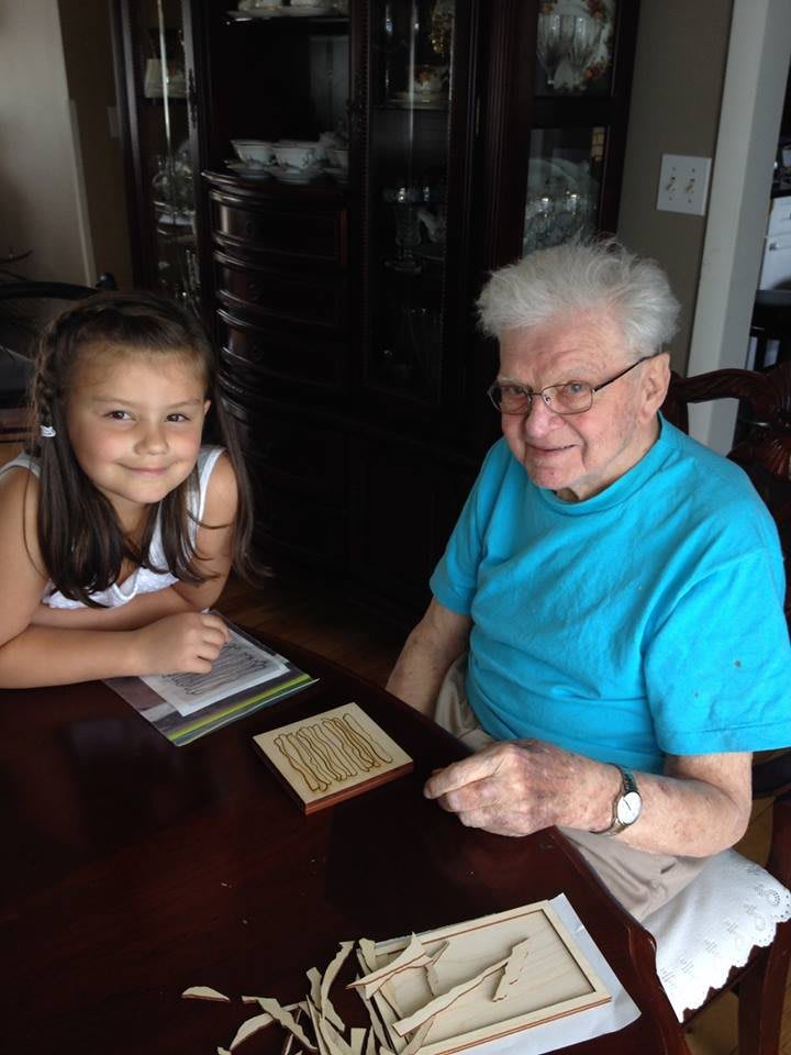 An elderly person and a child sitting at a table and smiling.