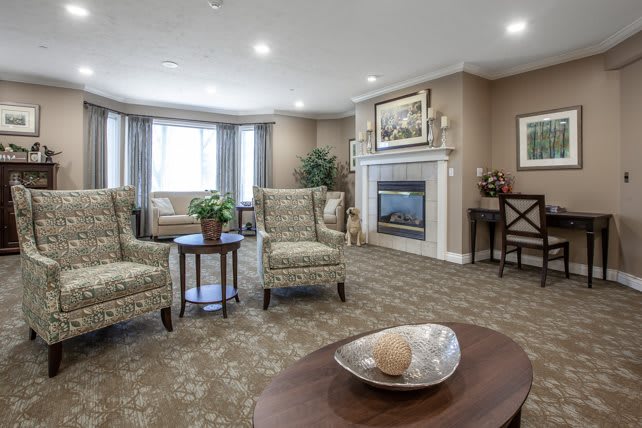 A cozy living room with a fireplace, comfortable chairs, and tasteful decor.