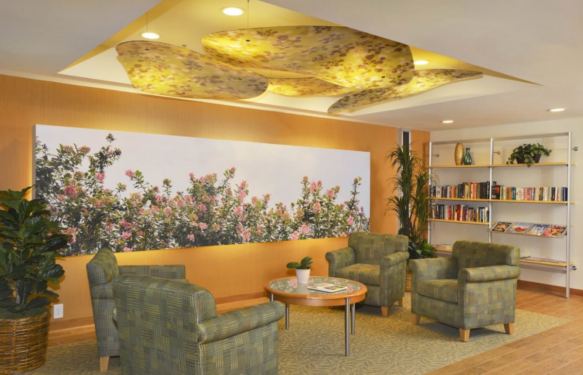 A cozy lobby with comfortable seating, floral artwork, and a bookshelf.