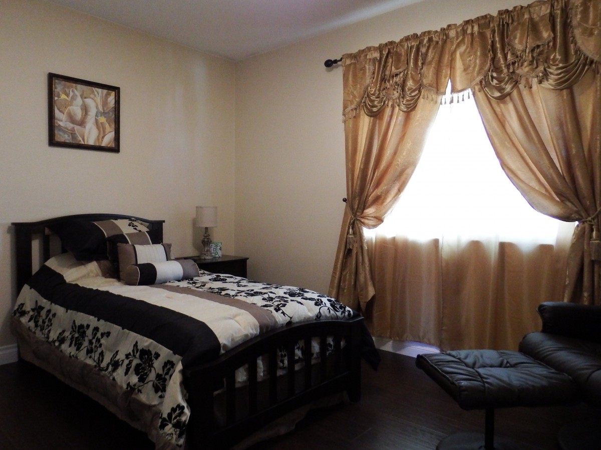 A cozy bedroom with dark furniture, decorative bedding, and elegant curtains.