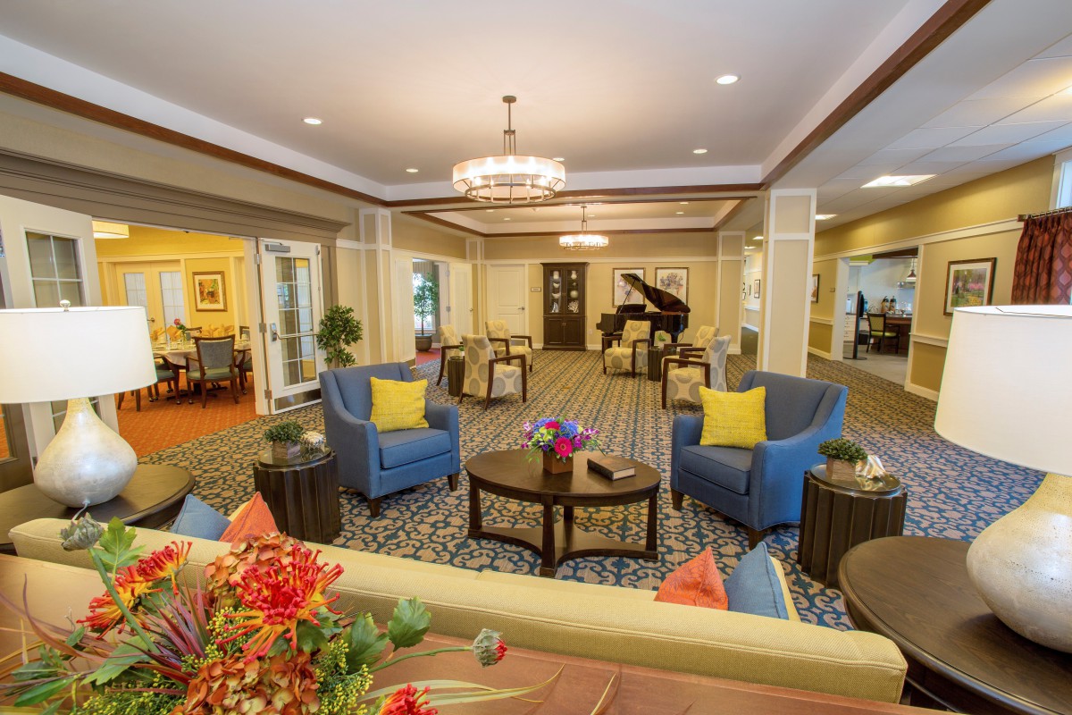 A spacious and elegantly designed living room featuring comfortable seating, a grand piano, and stylish decor.