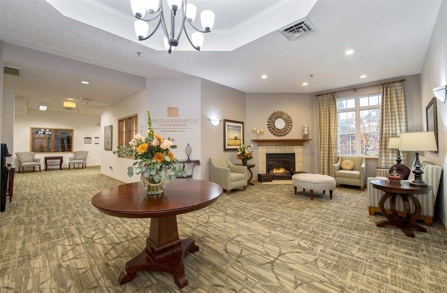 A cozy and elegantly decorated living room featuring a fireplace, comfortable seating, and a chandelier.